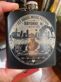 Black flask with a detailed design of a music festival in Bayonne, NJ held by a person.
